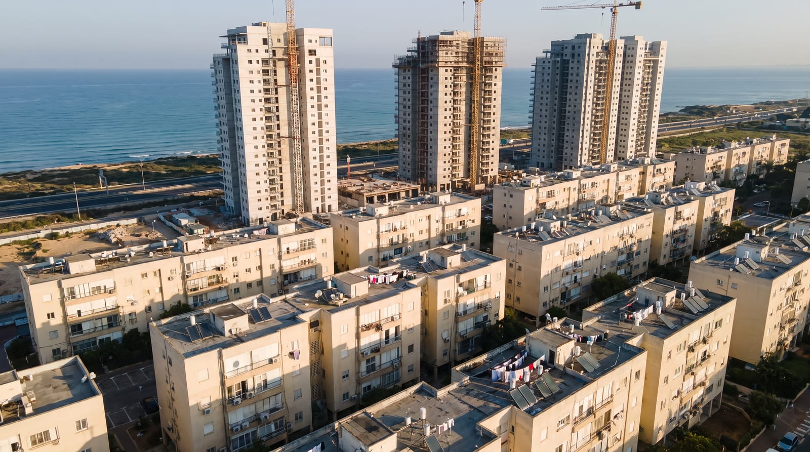מגדלי מגורים חדשים בבנייה לצד שיכונים ותיקים על חוף הים